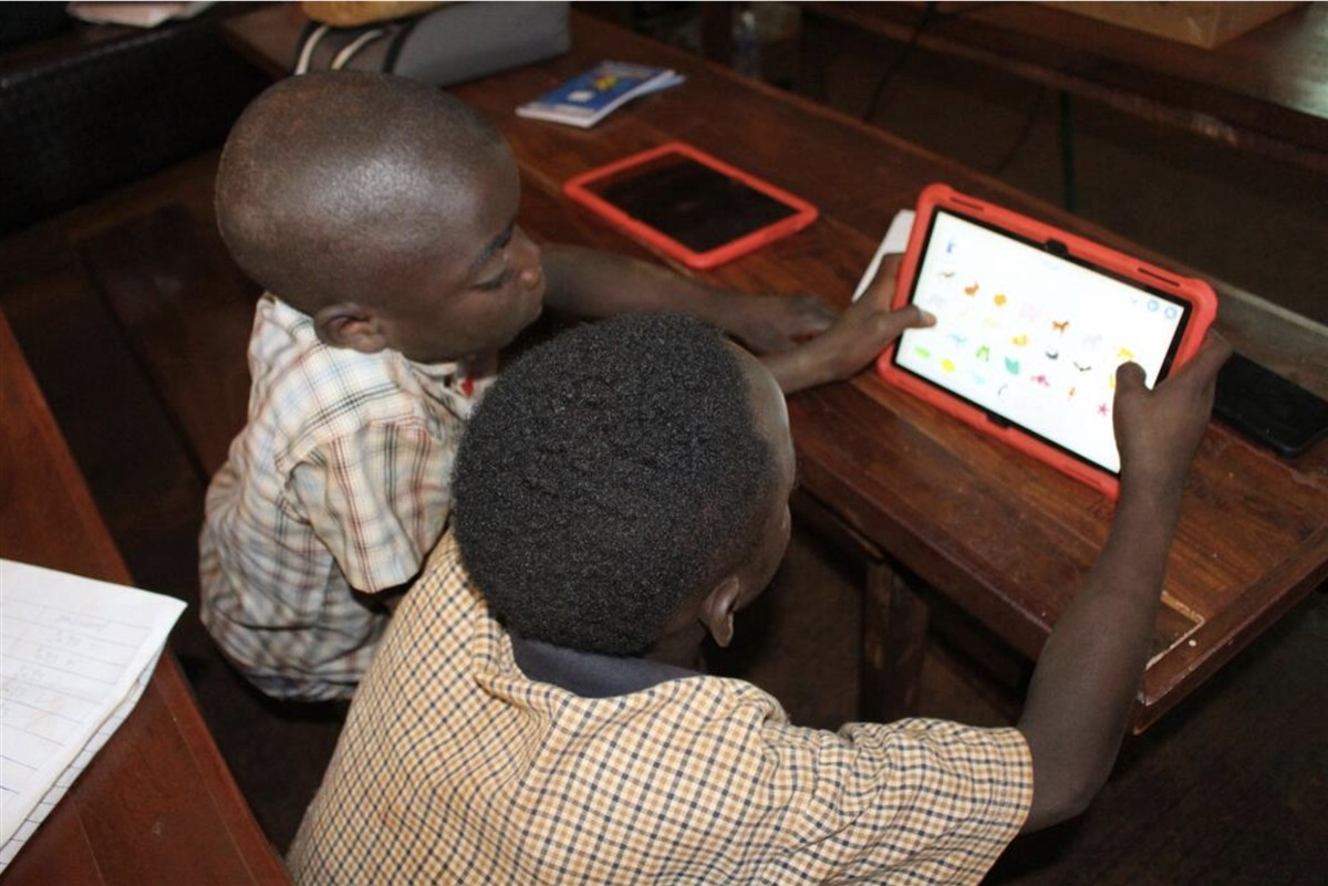 Two young boys work on a tablet in Tanzania